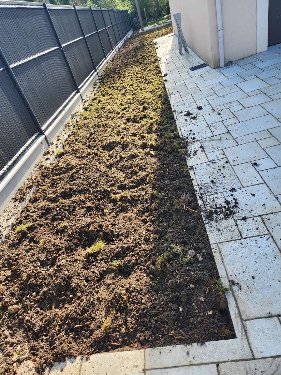 Préparation d'un massif fleuri le long d'une clôture par ALP Jardin en Essonne